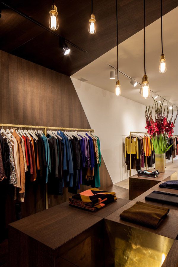 Màu gỗ tự nhiên cùng thiết kế ánh sáng dạng thả giúp mẫu thiết kế shop thời trang nữ có không gian quý phái hơn
